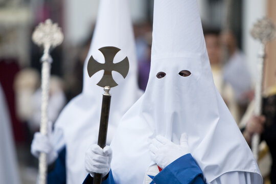 Portrait of a person with a traditional capirote and a cross at the Spanish Holy Week procession