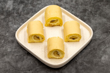 Banana roll cake. Roll cake with banana filling on a dark background. close up