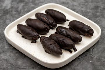 Special chocolate with dark outside and coconut inside. Dark chocolate with coconut filling on a dark background. close up