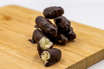 Special chocolate with dark outside and coconut inside. Dark chocolate with coconut filling on a wooden background. close up