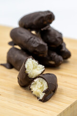 Special chocolate with dark outside and coconut inside. Dark chocolate with coconut filling on a wooden background. close up