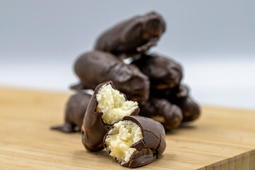Special chocolate with dark outside and coconut inside. Dark chocolate with coconut filling on a wooden background. close up