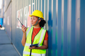Black female dock worker control loading containers box from cargo at warehouse container yard. Marine and carrier insurance concept. logistic shipping yard
