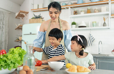 Asian young single mother with son and daughter in kitchen. Enjoy family activity together.