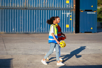 Black female dock worker walking go to work at warehouse container yard. Marine and carrier insurance concept. cargo shipping container box in logistic shipping yard