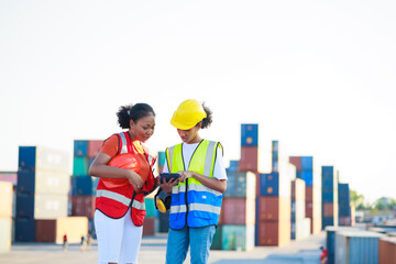 Two friends Black female dock worker relax talking in break time at warehouse container yard. Marine and carrier insurance concept. logistic shipping yard