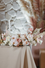 Banquet table is decorated with plates, cutlery, glasses, candles and flower arrangements