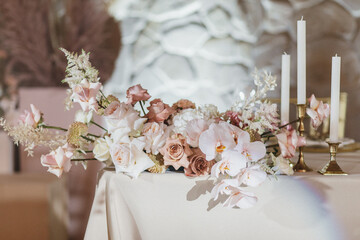 Banquet table is decorated with plates, cutlery, glasses, candles and flower arrangements