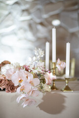 Banquet table is decorated with plates, cutlery, glasses, candles and flower arrangements
