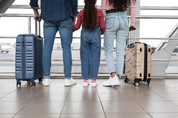 Parents And Little Daughter Waiting In Airport With Suitcases, Rear View