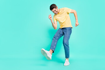 Full length photo of optimistic brunet young guy dance wear t-shirt jeans sneakers isolated on turquoise background