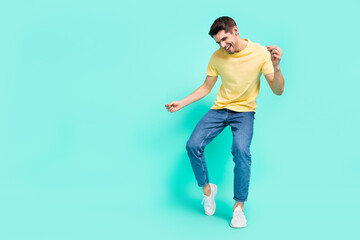 Full size photo of cute brunet young guy dance wear t-shirt jeans shoes isolated on turquoise background