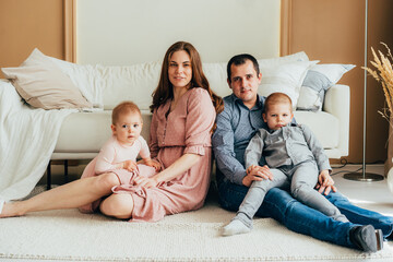 Happy mother and father embracing with daughter and son while sitting on floor at studio.