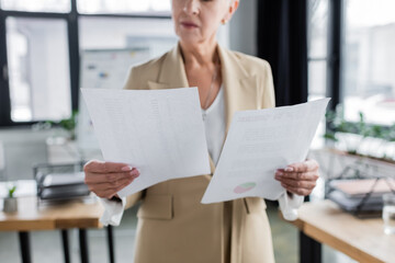 partial view of blurred economist holding documents in office.