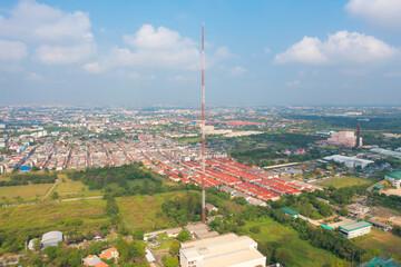 Obraz premium Aerial view of TV antenna in the middle of a city , red roofs on a housing community, vacant lots, urban and rural view.