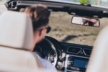 Photo of pretty attractive husband wear casual clothes sunglass riding cabriolet looking back mirror outside countryside