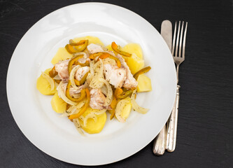 fish with onion, pepper and potato with sauce on the plate