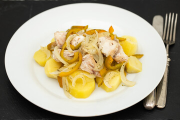 fish with onion, pepper and potato with sauce on the plate