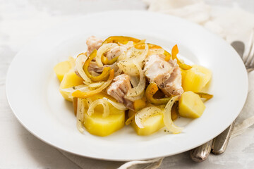 fish with onion, pepper and potato with sauce on the plate