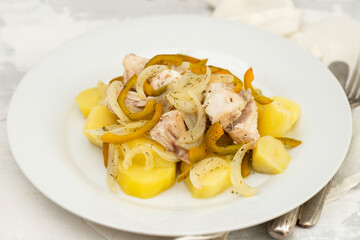 fish with onion, pepper and potato with sauce on the plate