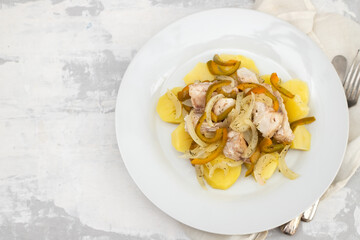 fish with onion, pepper and potato with sauce on the plate