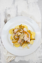 fish with onion, pepper and potato with sauce on the plate