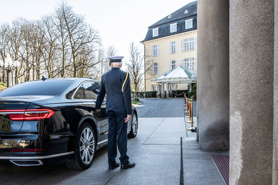 Ein Kompaniefeldwebel (Spieß) der Deutschen Marine steht an der rechten Seite einer Limousine, die vor dem Grand Hotel Petersberg vorgefahren ist. Gleich wird er die Wagentür öffnen. 
  
