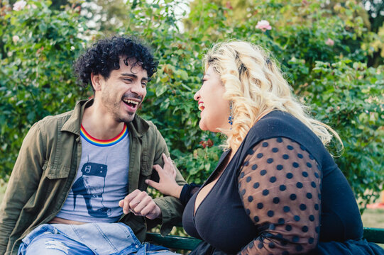 man and woman sitting outdoors laughing and enjoying together.