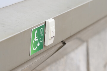 A staff call button for people with reduced mobility on a green sign