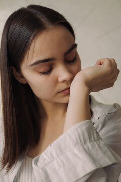 Delicate dreamy woman smelling essential oil scent from wrist while enjoying aromatherapy with closed eyes 