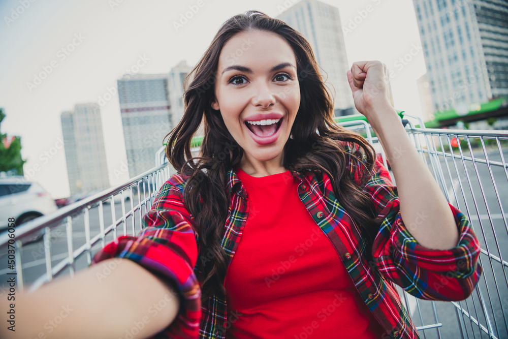 Sticker Self-portrait of attractive cheerful trendy lucky girl sitting in cart having fun rejoicing good mood great sale outdoors