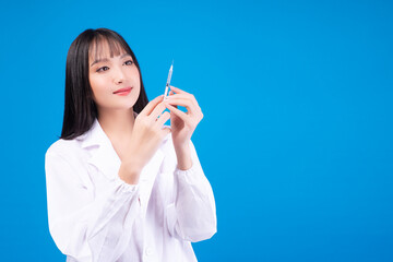 Obraz premium Doctor or nurse Asian woman wear uniform lab arms crossed holding syringe in own hands while standing over isolated blue background. Vaccine immunization disease health care concept.