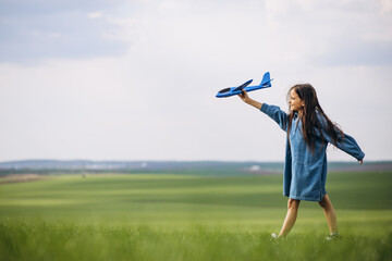 Little girl playing with toy plane in the field