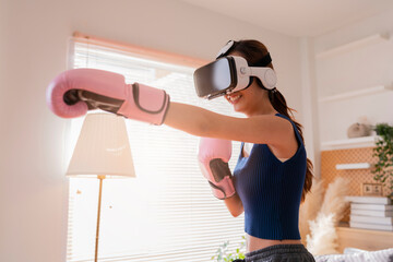 Virtual Metaverse Augmented Reality asian female adult working out boxing in VR headset aerobic...