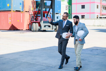 Man manager and male Supervisor dock cargo checking and working at container yard port of import and export goods. Unity and teamwork concept