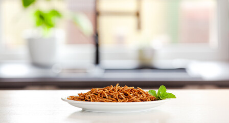 Snack insect on white plate with mint decoration and Kitchen Background. Mealworms crustaceans...