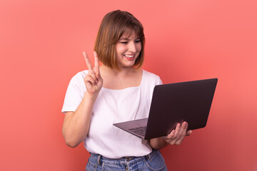 Portrait of attractive trendy lucky cheery girl agent broker using laptop rejoicing accomplishment isolated on pink pastel color background