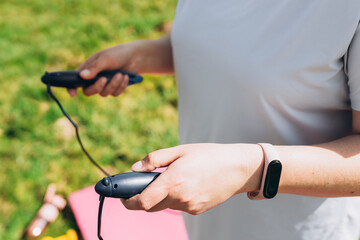 Close up of woman jumping, girl using skipping rope in park, summer sunny day