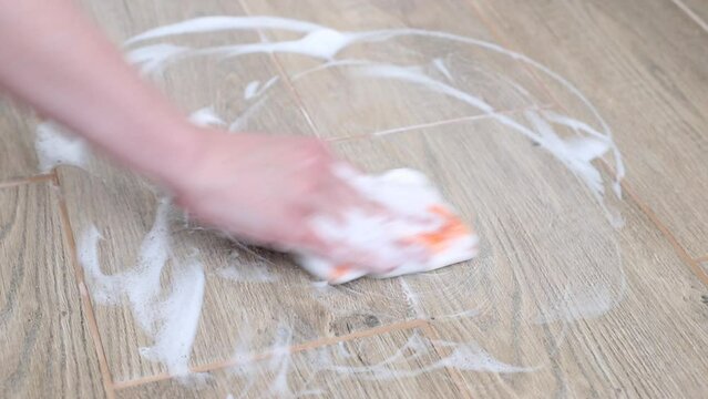 a housewife washes the parquet with a sponge with foam. close-up. cleaning