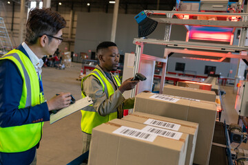 Asian manager with checklist looking at african american young man scanning barcode on cardboard box