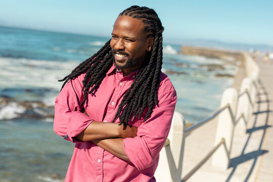 Smiling african american man with standing with arms crossed at promenade on sunny day