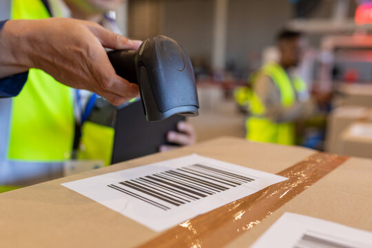 Cropped hand of asian mature male worker scanning barcode on cardboard box with reader