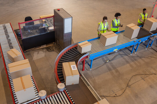 High Angle View Of African American Young Man And Woman With Asian Mature Man Processing Boxes