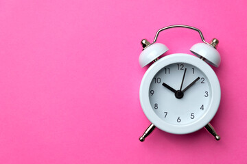 White analog alarm clock isolated on pink background. Concept of time management. Copy space....