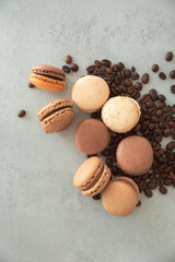 Chocolate hazelnut macarons and coffee beans on a gray background, top view, vertical photo of confectionery with copy space.