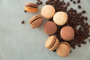 Chocolate hazelnut macarons and coffee beans on a gray background, top view, copy cpace. French macaroons