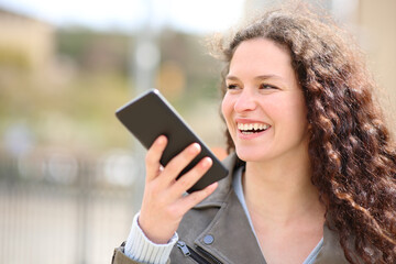 Happy woman laughing using voice recognition on phone