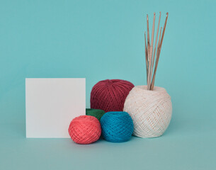A closeup shot of red, purple, and blue knitting yarns and crochet hooks