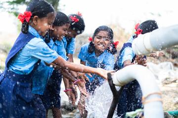 group of village school girl kids playing in water near paddy field - concept of happiness, fun and carefree lifestyle