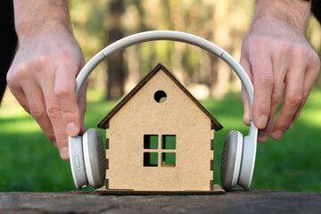 Man placing white headphones on a toy house model